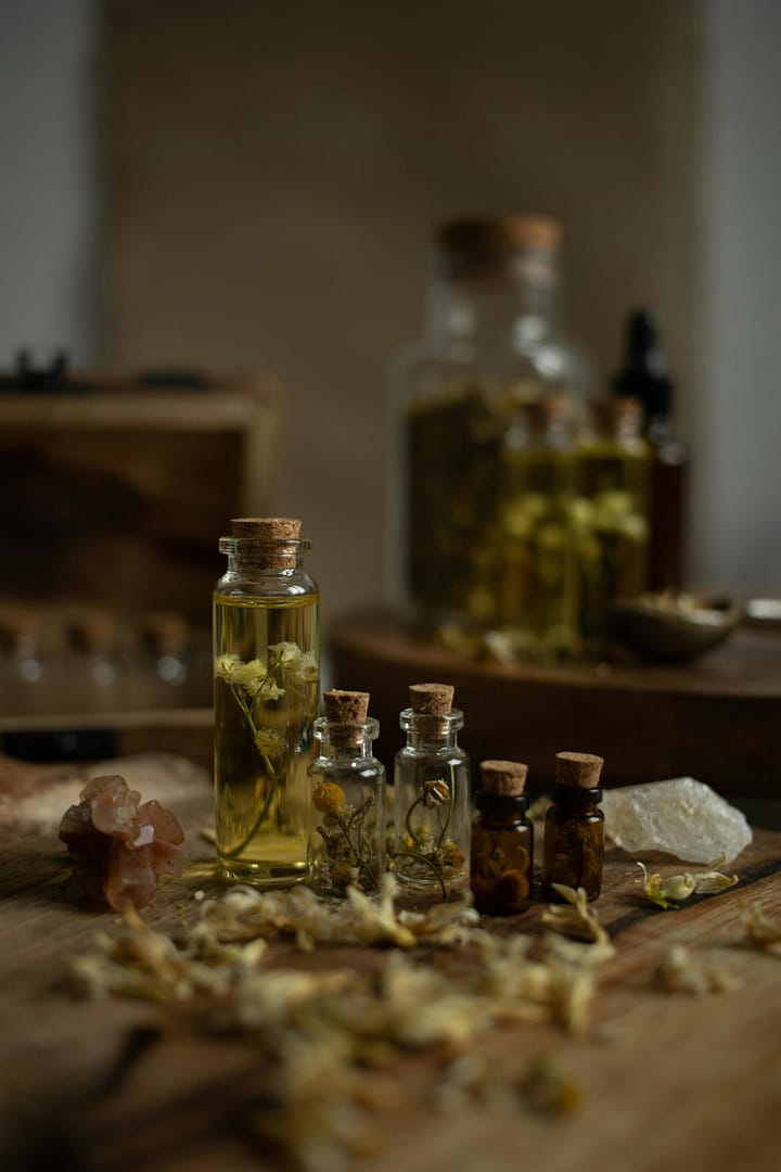 glass bottles with aromatic herbs on a wooden table, perfect for aromatherapy themes.